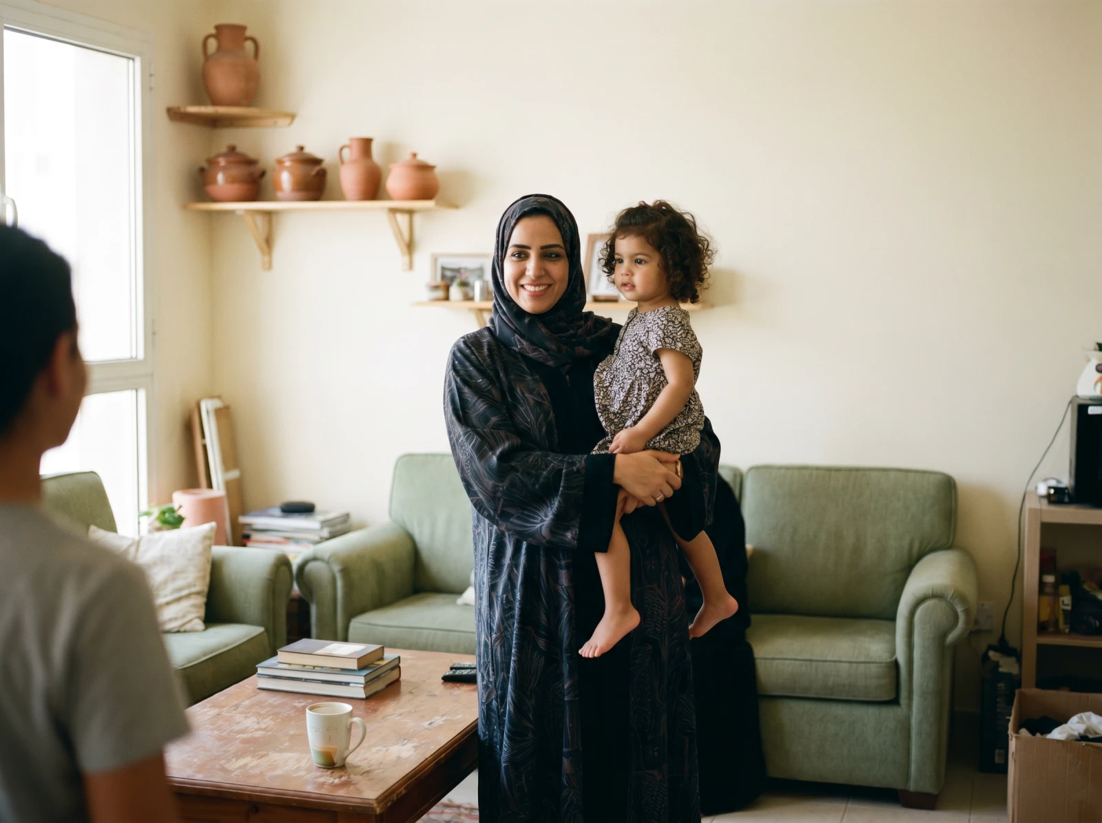 A parent holding a laughing young child by a bright window
