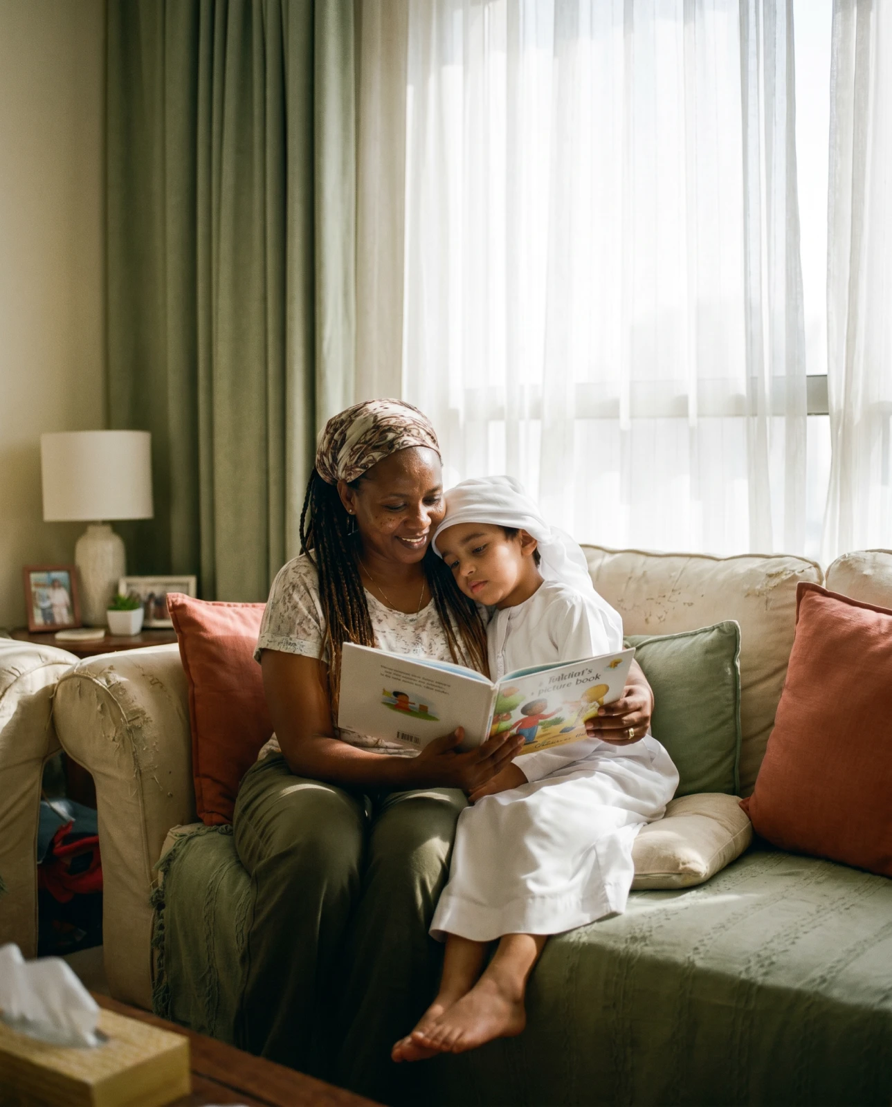 A caregiver reading a picture book with a young child in warm light